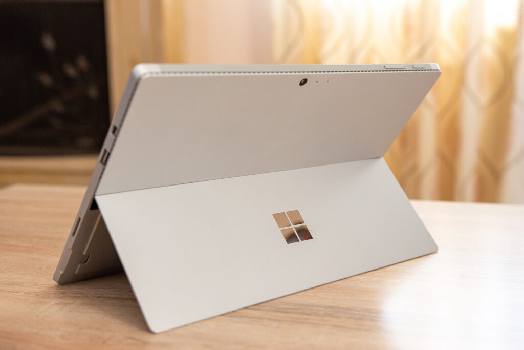 Microsoft Surface tablet positioned on a wooden surface, showcasing its adjustable kickstand and logo, relevant to discussions about new Microsoft Surface models and their features.