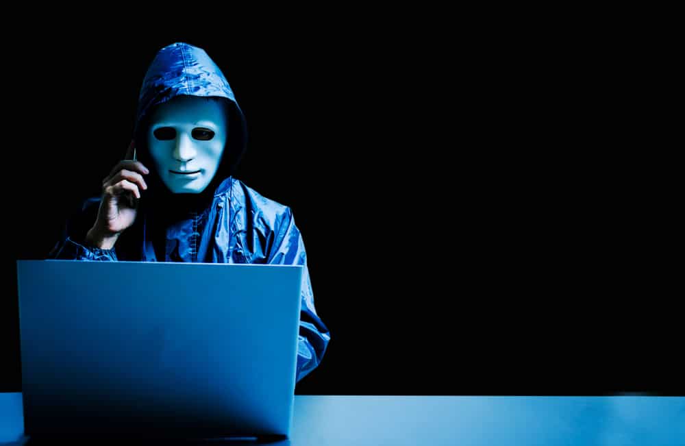 Anonymous computer hacker in white mask and hoodie