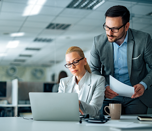 Business professionals collaborating at a laptop in a modern office setting, emphasizing teamwork and productivity in IT operations.